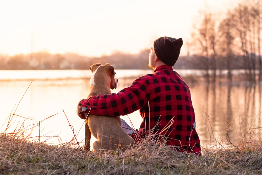 koira ja omistaja järven rannalla nurmikolla